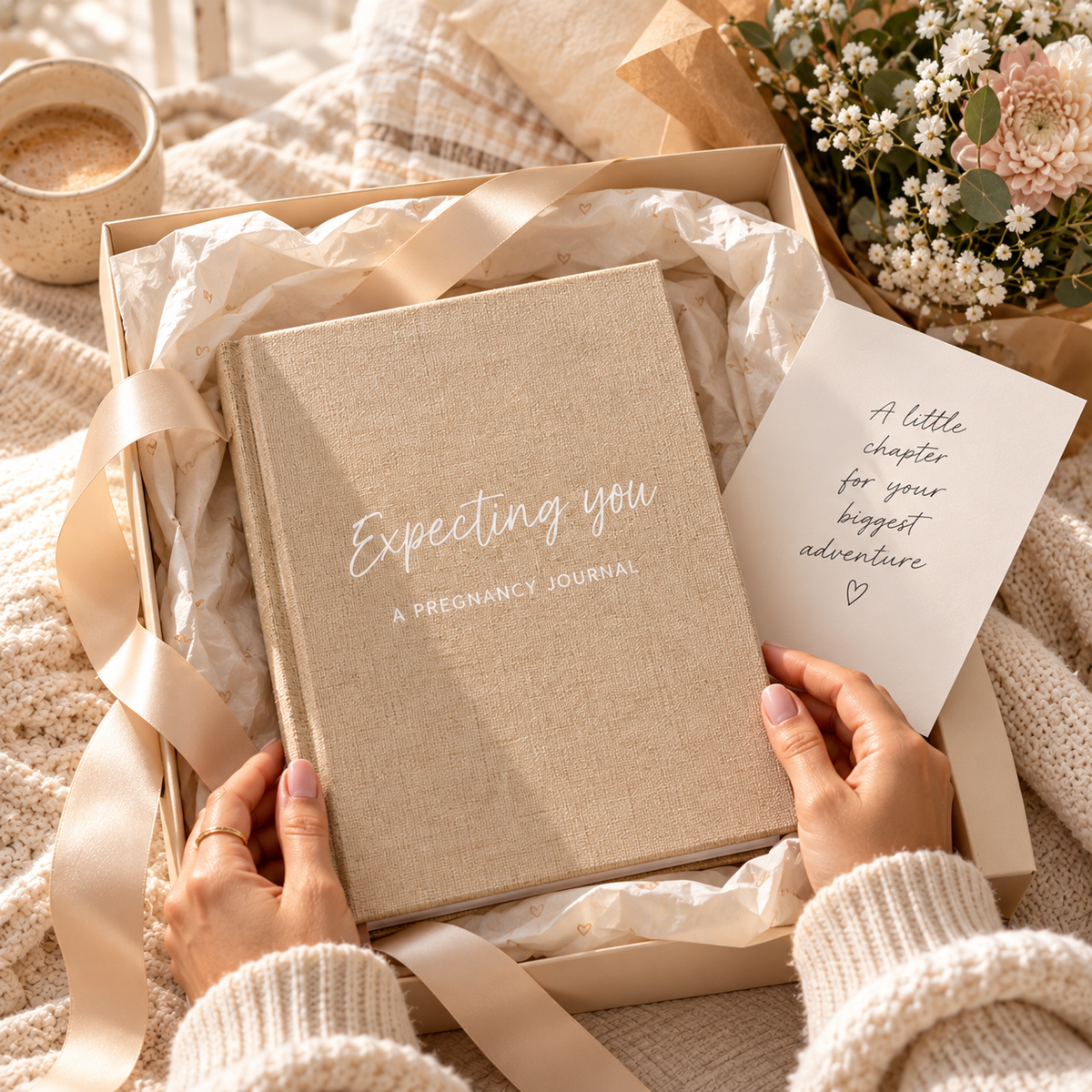 Hands holding the Expecting You pregnancy journal with its linen cover